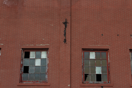 Two large industrial windows with broken frames in a red brick facade, horizontal aspectの写真素材