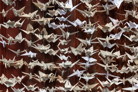 Very close view of 1000 origami folded paper cranes sculpture against a background of old red tin siding, horizontal aspectの写真素材