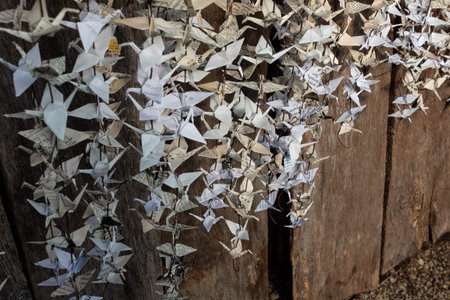 Paper cranes hanging from strings against old barn wood, vintage ephemera, folded origami, selective focus, horizontal aspectの写真素材