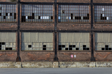 Straight on view of old steel mill warehouse industrial site, broken windows, horizontal aspectの写真素材