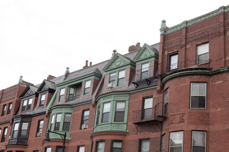 Front of old brownstone apartment buildings showing a variety of architectural styles and finishes,...