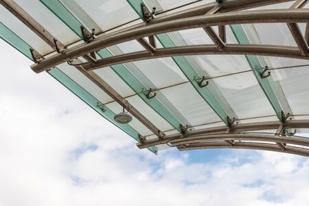 Top edge of modern metal and glass cover before blue sky with clouds, horizontal aspectの写真素材