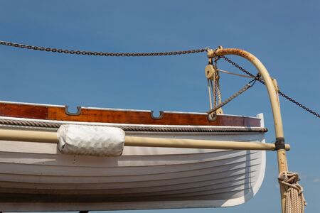 Old wooden lifeboat hoisted up on the side of an old tall ship, rigging details, horizontal aspectの写真素材