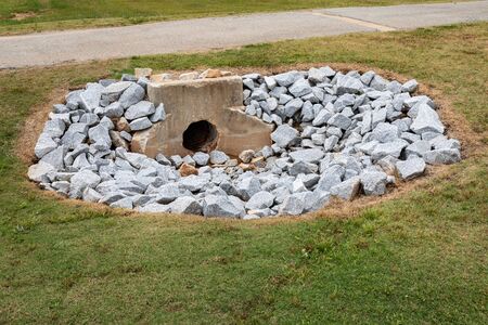 Aged cast concrete headwall for storm water runoff surrounded by new rocks, environmental safety, green grass copy space, horizontal aspectの写真素材