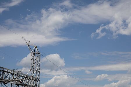 Metal truss structure of an electrical power substation against a dramatic blue sky with white clouds, creative copy space, horizontal aspectの写真素材