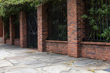Tall brick and wrought iron wall beside a slate stone walkway, old architectural details, copy...