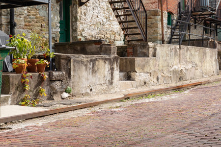 Red brick street with rusted metal curb edge, patched concrete retaining wall, metal stairs, horizontal aspectの写真素材