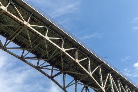 View from underneath an old arch highway bridge silhouetted against a blue sky, creative copy space,...