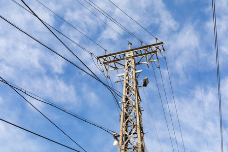 Tall metal electric power tower with lines running in multiple directions against a hopeful blue...