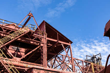 Abandoned industrial site, stairs and open walkways with rusted metal and peeling paint against a beautiful blue sky, horizontal aspectの写真素材
