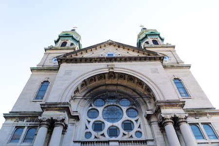 Straight on view of a gray stone church with verdigris copper cupolas, rose window, horizontal aspectの写真素材