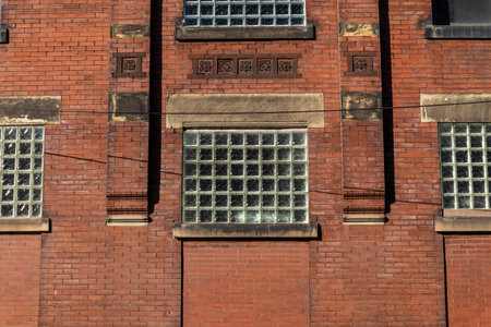 Facade of an old red brick commercial industrial building, decorative brick details and window...