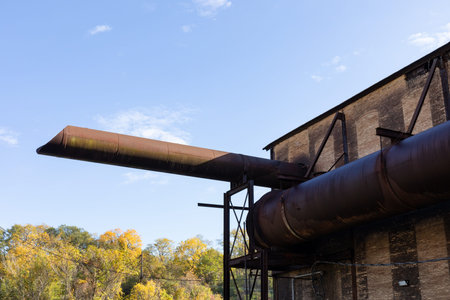 Giant pipe tubes wrapping and emanating from an old industrial warehouse building, fall season...