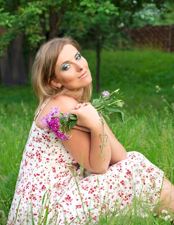 Woman sitting on the grass with flowersの写真素材