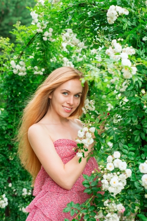 Woman stands near a garden of white rosesの写真素材
