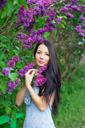 Beautiful brunette woman standing near the lilacsの写真素材