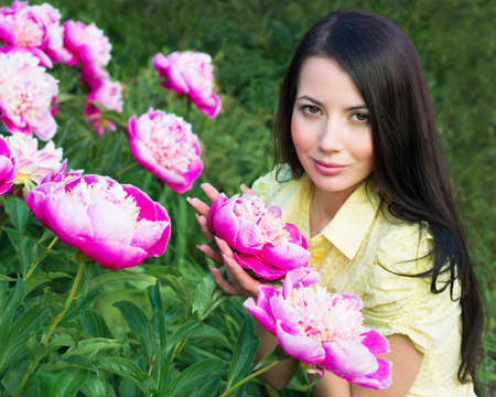 Young woman with pink peoniesの写真素材