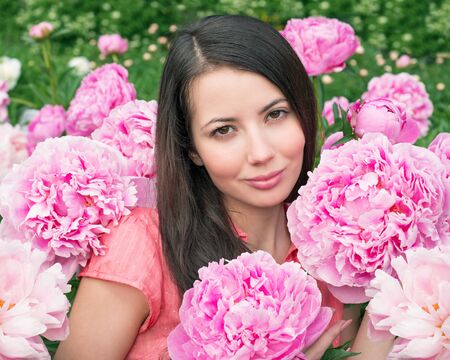 Young woman with pink peoniesの写真素材
