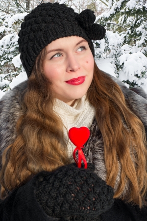 Young woman holding red heart in winterの写真素材