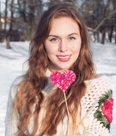 Beautiful woman holding a pink heart and smilingの写真素材