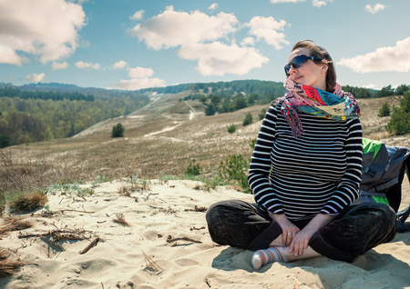 Woman tourist sitting sandy hillの写真素材