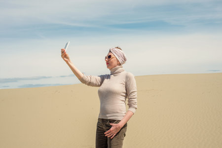 Woman catches link on the smartphone in the desertの写真素材