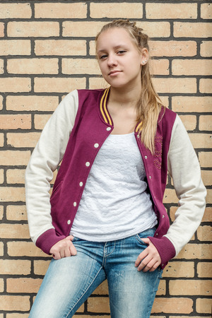 Teen girl standing near brick wallの写真素材
