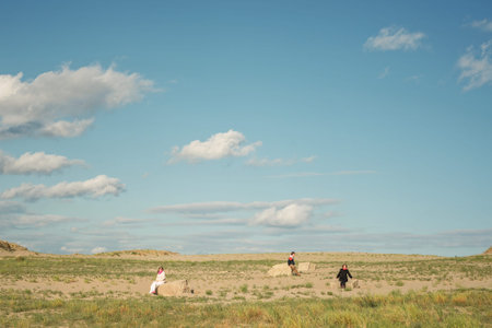 Landscape with people. Three people sitting in a field on the rocksの写真素材