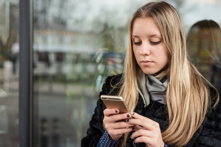 Teen girl with long hair with a smartphoneの写真素材