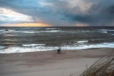 Two people standing on the sea and the clouds photographed on a smartphoneの写真素材