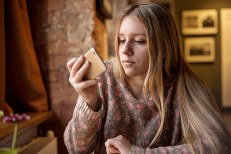 Teen girl with long hair with a smartphoneの写真素材