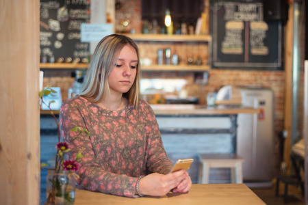 Girl with long hair sitting at a table in a cafeの写真素材