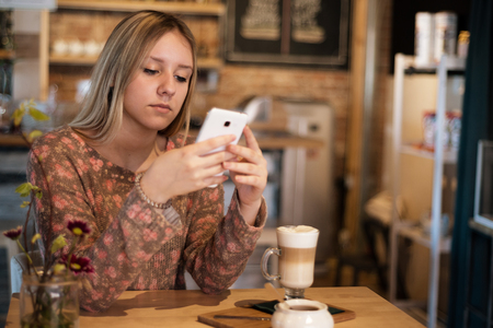 Girl with long hair sitting at a table in a cafeの写真素材