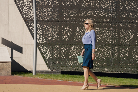 Blonde woman walking near a modern buildingの写真素材