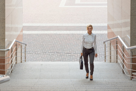 Business woman in pants with a briefcase climbs the stairsの写真素材