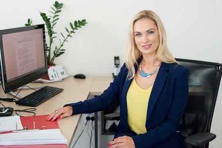 Blond woman is sitting at a table in the officeの写真素材