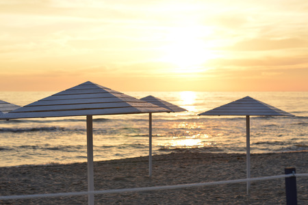Wooden beach umbrellas on the beach at sunsetの写真素材