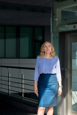 Blonde woman in a skirt stands with a phoneの写真素材