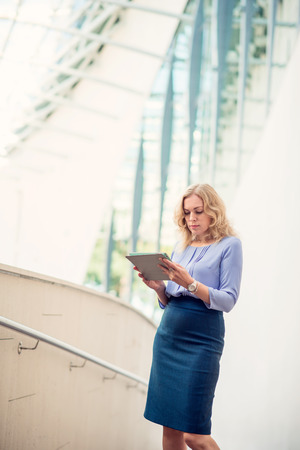 Woman blonde with a digital tablet on a background of modern architectureの写真素材