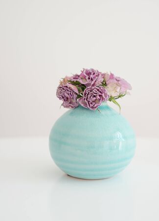 Flowers pink dry roses in a round turquoise vaseの写真素材