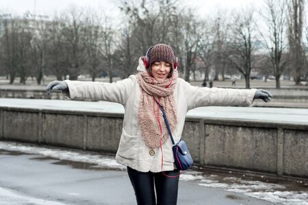 Woman in a hat and headphones listening to music and dancing on the streetの写真素材