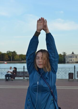 Young woman in headphones in the evening dancing on the streetの写真素材