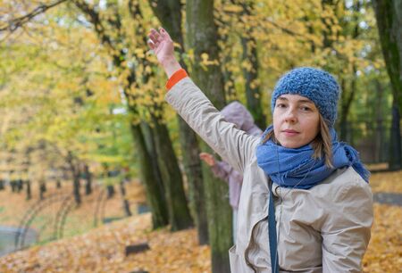 Young woman in hat and headphones dancing in autumn parkの写真素材