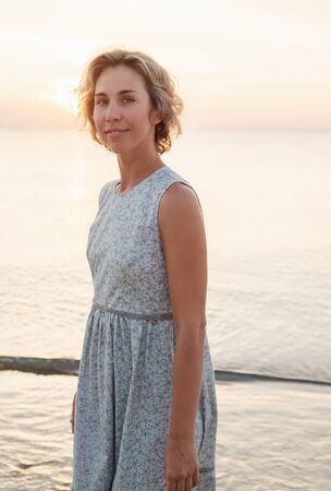 Natural portrait of a blonde woman in a dress near the seaの写真素材