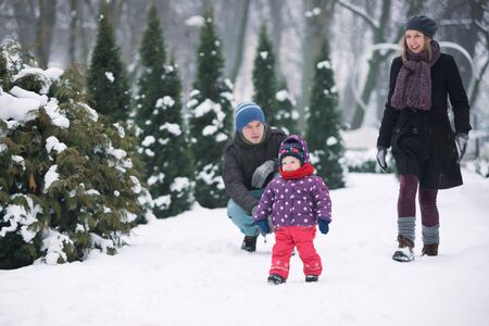 Family with a small child walk in the park in winterの写真素材