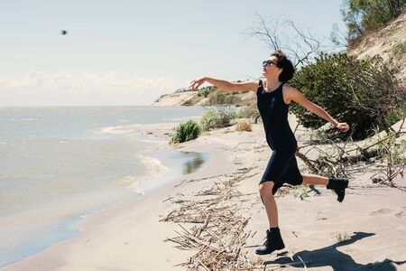 Young woman throws stones at seaの写真素材