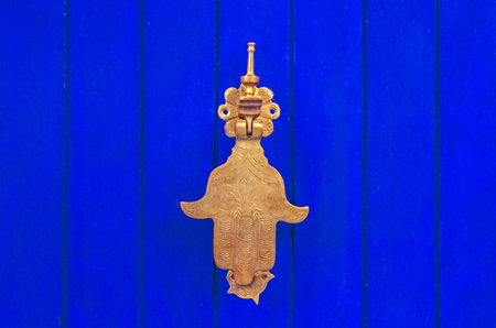 Gold hand of metal on a blue textured background in chefchaouenの写真素材