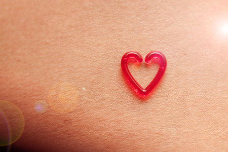 One red plastic heart on skin background with space.の写真素材