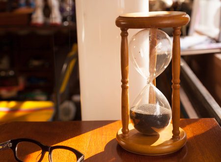 Sandglass, hourglass on table near window.