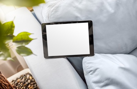 Black ipad in landscape position on a blue leather sofa.の写真素材